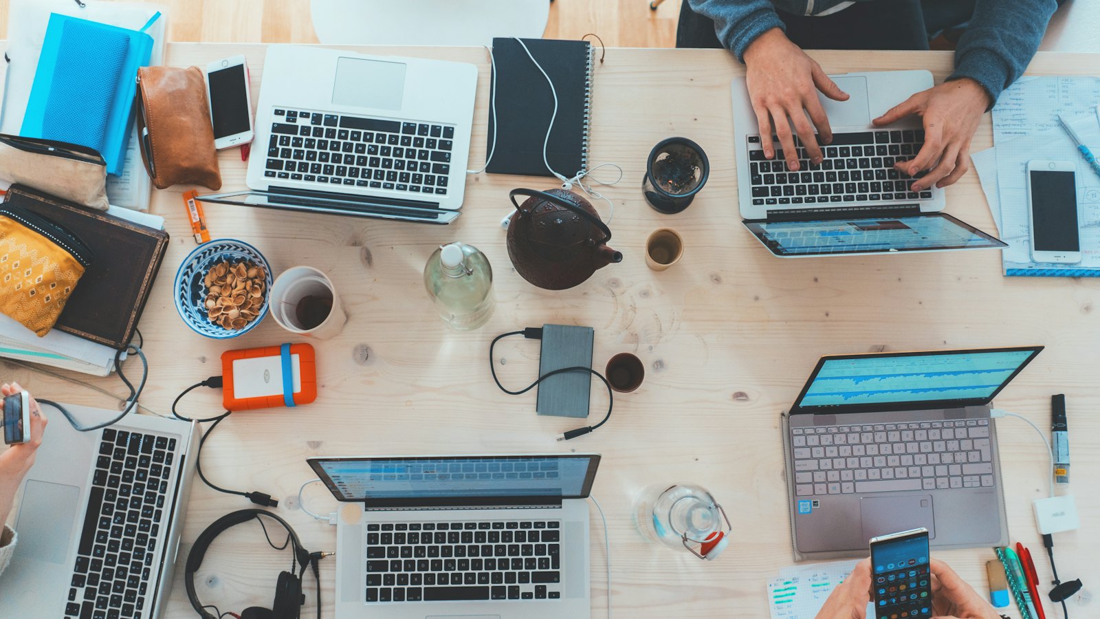 Overhead view of a team working on laptops around a shared desk
