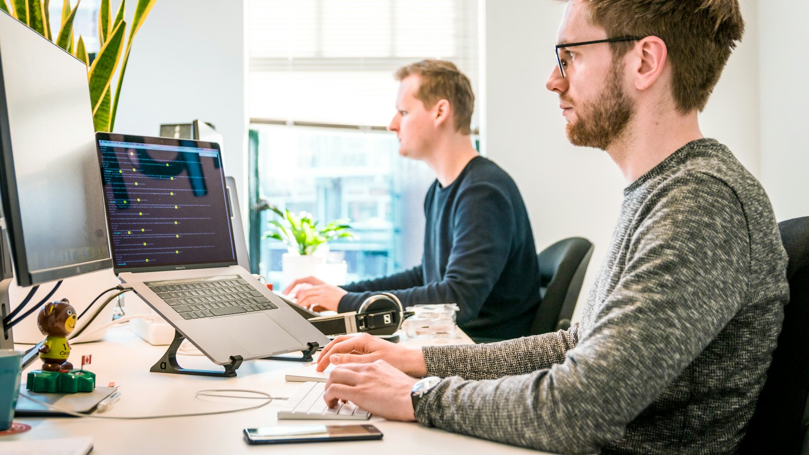 Two colleagues working together at their screens